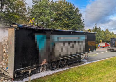Ein Feuerwehrmann befindet sich auf dem Dach des LKW-Aufliegers.