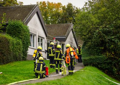 Feuerwehrleute mit Atemschutzflaschen auf dem Weg zum Kindergartengebäude.
