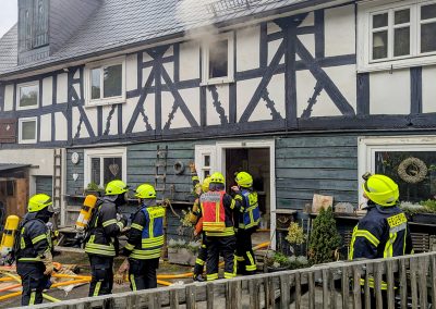 Feuerwehrleute mit Atemschutz vor dem Eingang zum Gebäude