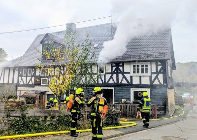 Feuerwehrleute mit Atemschutz vor dem brennenden Gebäude