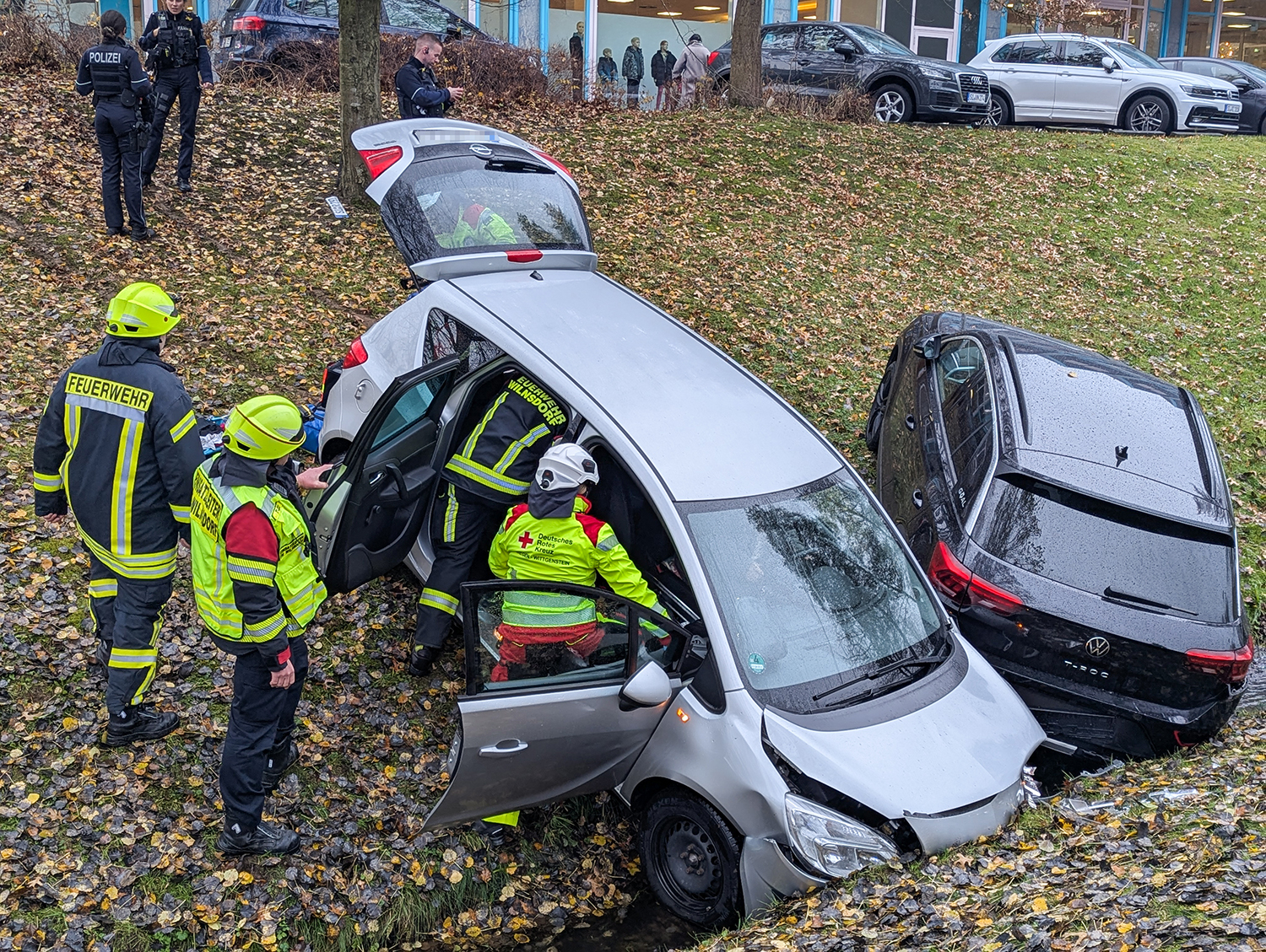 Zwei Fahrzeuge stehen im Bachbett. Einsatzkräfte kümmern sich um die Bergung der Seniorin.