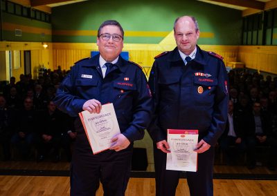 Ehrung für 40-jährige aktive Mitgliedschaft: Zwei Feuerwehrleute werden ausgezeichnet und zeigen ihre Urkunden.