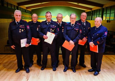 Ehrung für 50-jährige aktive Mitgliedschaft: Sieben Feuerwehrleute werden ausgezeichnet und halten ihre Urkunden in den Händen.